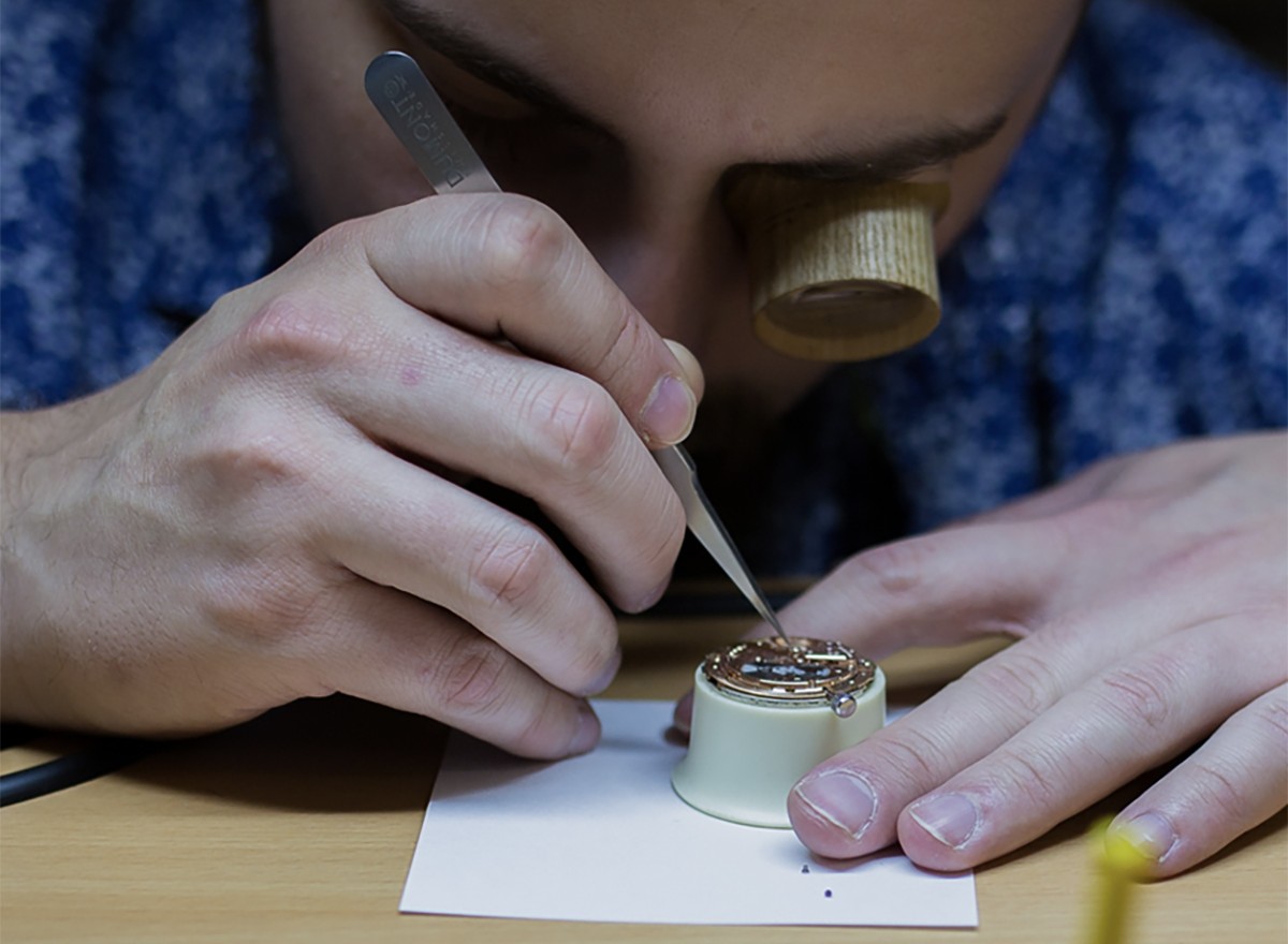 Uhrmacher arbeitet mit der Pinzette an einer geöffneten Armbanduhr Uhrmachermeister an der geöffneten Armbanduhr