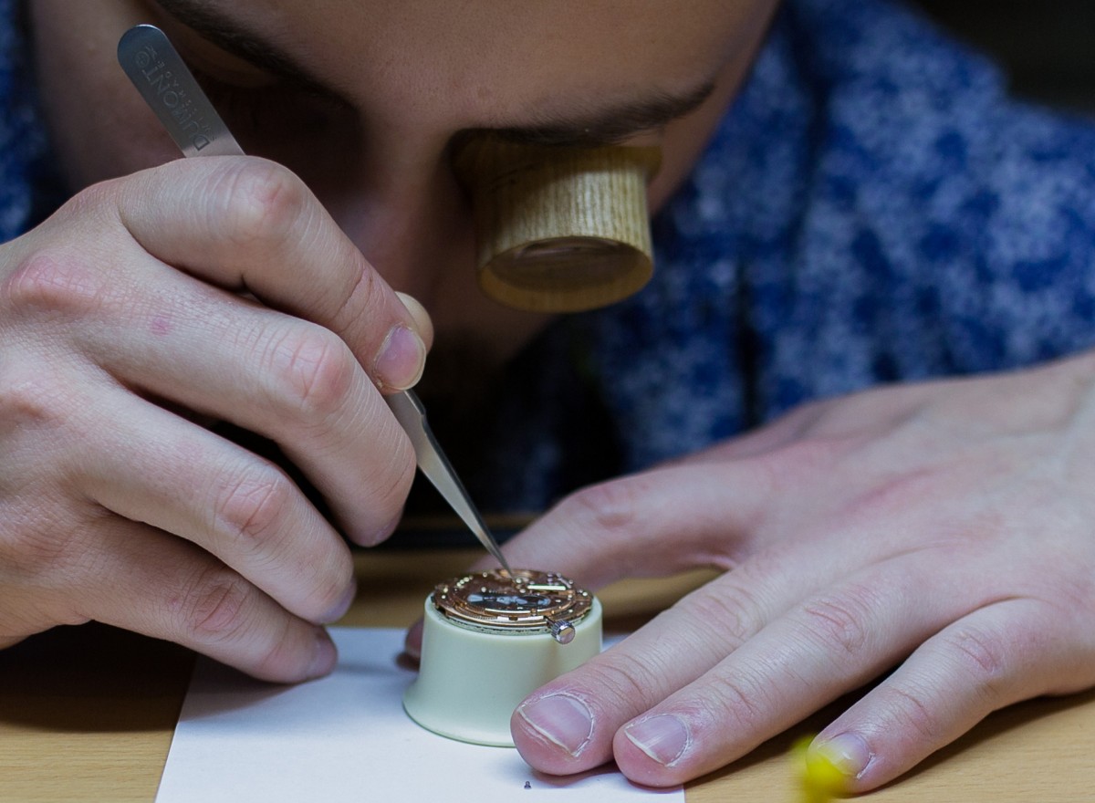 Nahaufnahme einer Uhrenreparatur mit der Pinzette in der Werkstatt